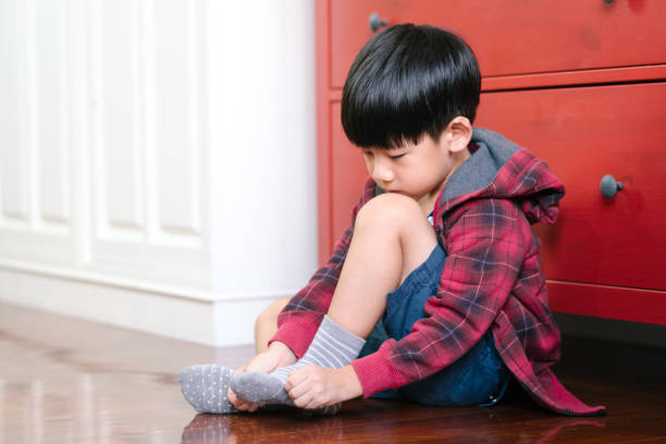 istock Cute Asian boy getting dressed for school, putting on socks, smiling with happiness to go back to school 1308546334