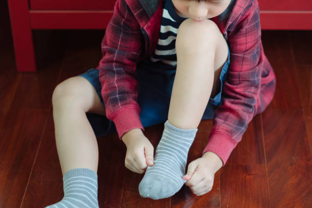 istock Cute Asian boy getting dressed for school, putting on socks, smiling with happiness to go back to school 1308546335