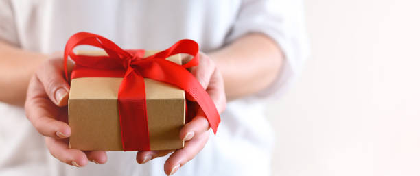 istock Woman holding gift box with red bow 1308546584