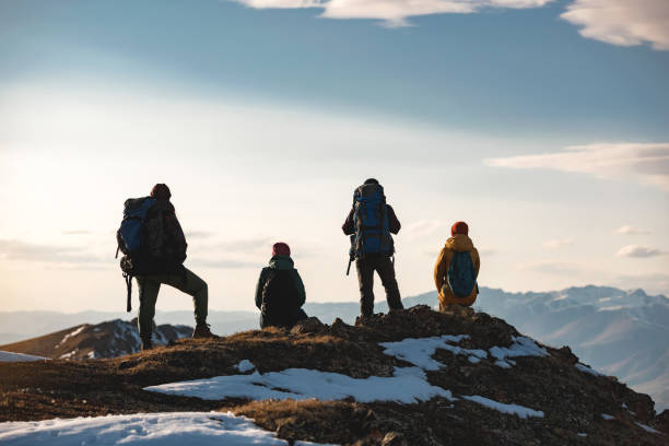 Four hikers are relaxing on mountain top Group of four hikers are relaxing on mountain top. Unrecognizable tourists with backpacks western siberia stock pictures, royalty-free photos & images