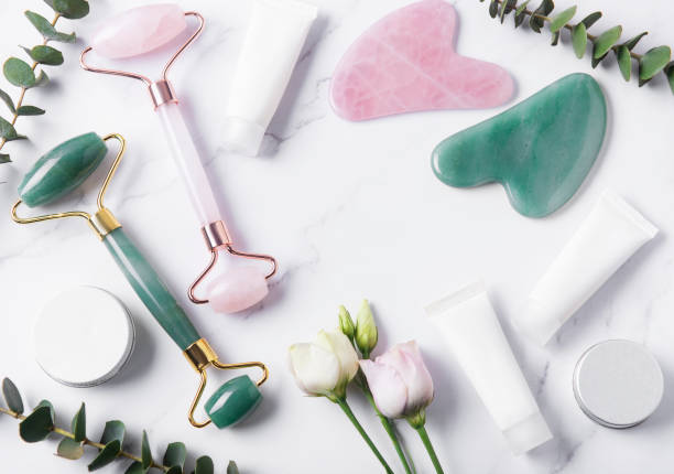 istock Cosmetic products cream tubes,  face roller and eucalyptus  on marble background. 1308551619