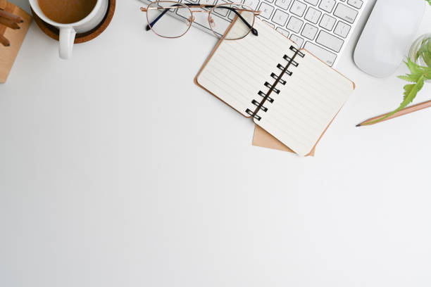 istock Top view of white office desk with keyboard, coffee cup, glasses, notebook and copy space. 1308551658