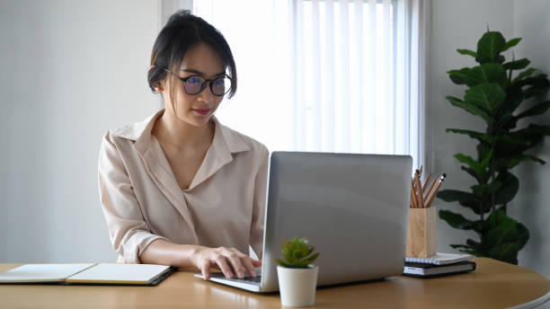 istock Confident young woman office worker in eyeglasses working on laptop computer in office. 1308552411