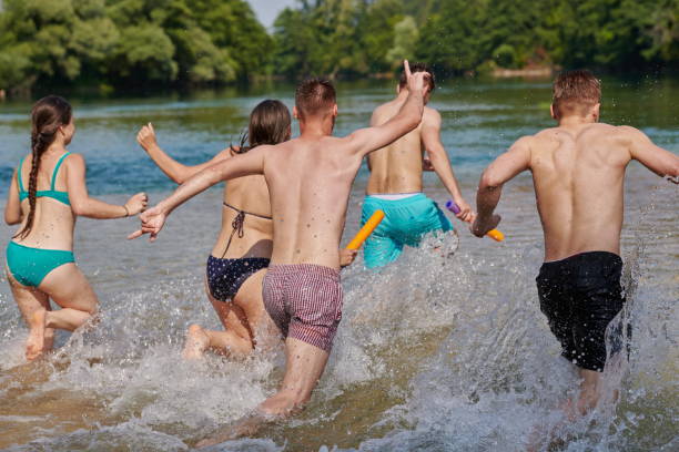 gruppo di amici felici che si divertono sul fiume - men beach running shirtless foto e immagini stock