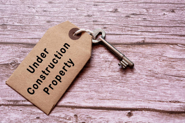 istock Text on brown tag with key on wooden table - Under construction property 1308557826