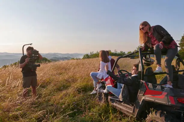 cameramen with professional equipment film a group of young people enjoying the mountain riding a buggy car