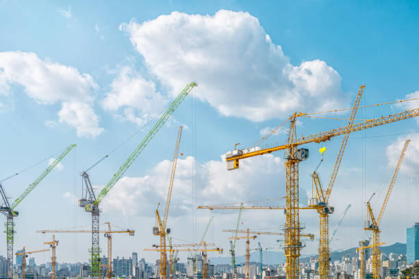 istock Panorama with many tower cranes in clear blue sky with clouds 1308559940