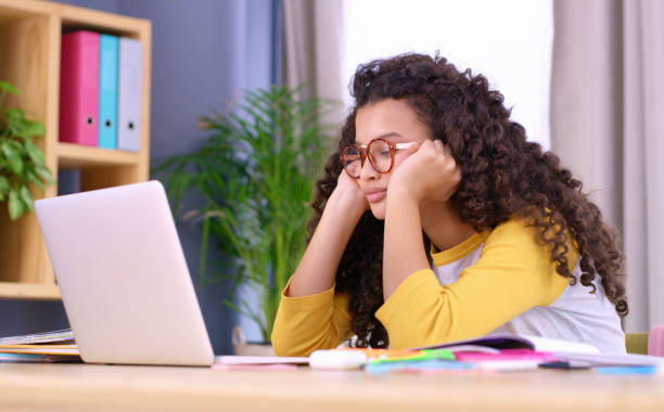 Her massive pileup of homework is causing some serious burnout Shot of teenage girl looking bored while doing her school work pileup stock pictures, royalty-free photos & images