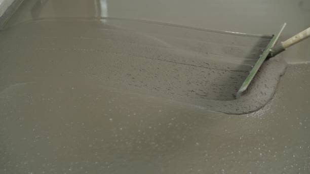 istock Self-leveling cement floor. Leveling the floors with a cement mixture. The process of leveling the mortar on the floor. The worker levels the self-filling liquid floor with a trowel. Leveling the floor with a trowel. 1308561049