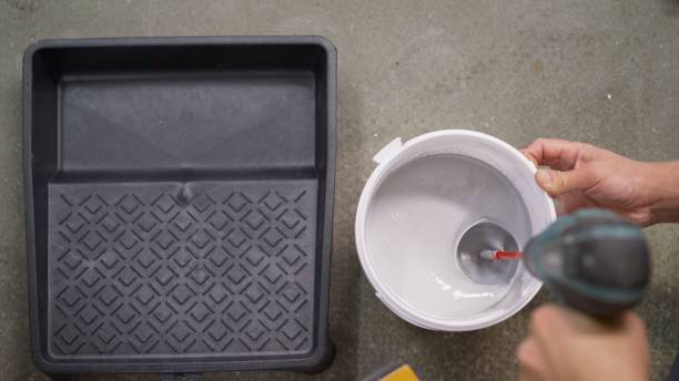 istock The white paint is mixed in a bucket with a drill. Drill paddle mixer on a bucket with white paint, DIY tools and accessory, banner 1308561052