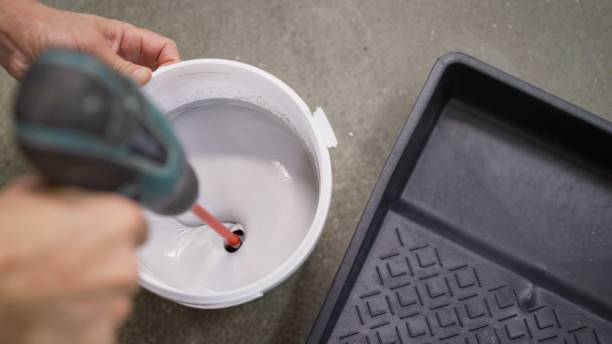 The white paint is mixed in a bucket with a drill. Drill paddle mixer on a bucket with white paint, DIY tools and accessory, banner