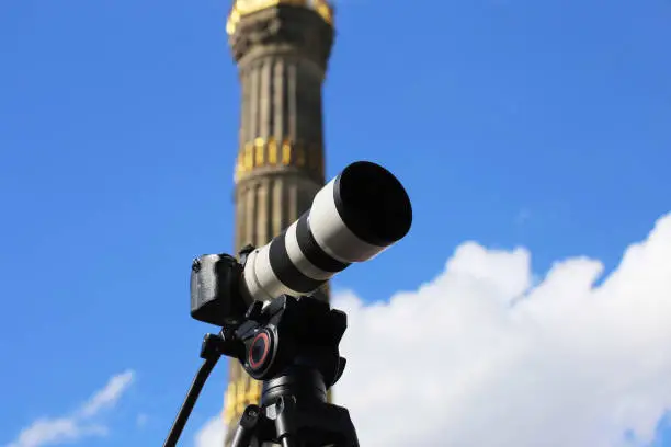 Berlin: Tripod with camera and telephoto lens in front of the Victory Column (Siegessäule)