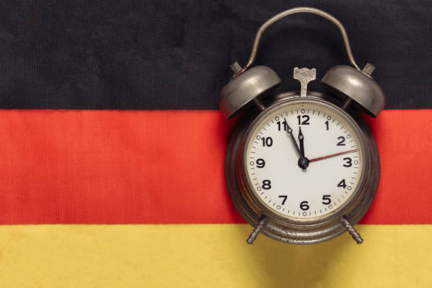 istock Vintage alarm clock on background of Germany flag 1308563431