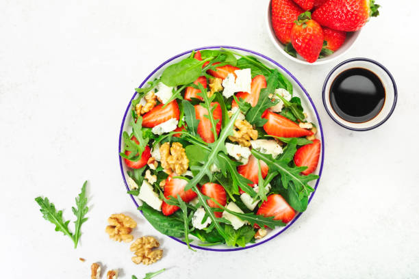 istock Summer Strawberry Salad. Spinach leaves, arugula, walnuts, blue cheese on gray background. Healthy food concept. Flat lay, top view 1308566231