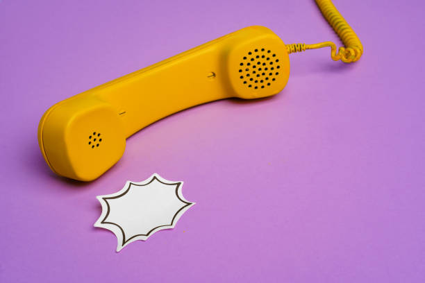istock Yellow landline phone with speech bubble on purple background 1308567050