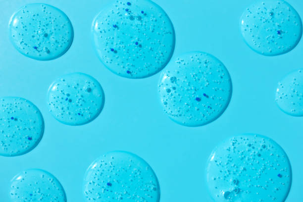 istock Clear gel cleanser spots on blue background. Cosmetic scrub texture with blue pilling particles. Beauty concept backdrop 1308568575