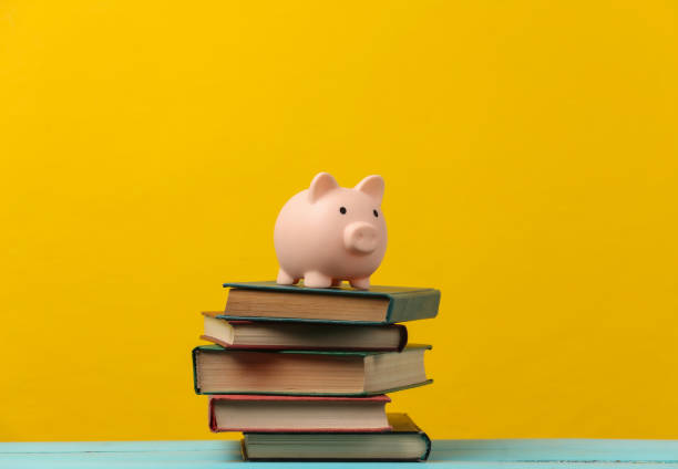 istock Piggy bank on a stack of books. Yellow background 1308569716