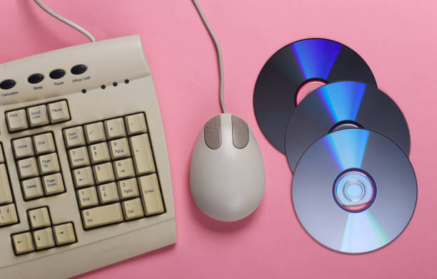 istock Old-fashioned retro keyboard CD's and pc mouse on pink pastel background. Top view 1308569781