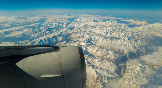 A view from a passenger window of a large aircraft traveling across the world on a holiday or business trip. The view of the awe inspiring French Alp mountains.