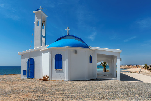 Traditional white chapel with a blue roof on the Mediterranean sea coast in Cyprus island, Mediterranean Sea.