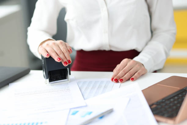 istock Businesswoman puts stamp on documents on work table 1308571754