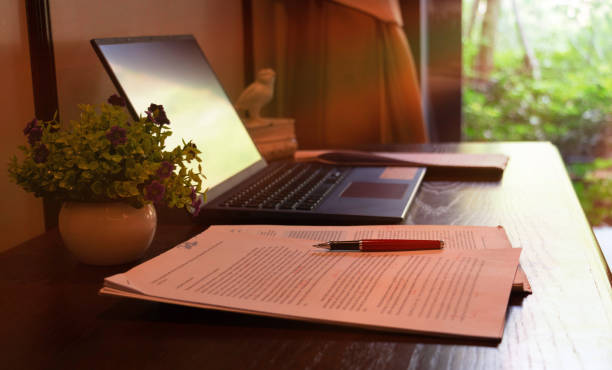 proofread red pen over blurred paperwork on wooden table with laptop manuscript stock pictures, royalty-free photos & images