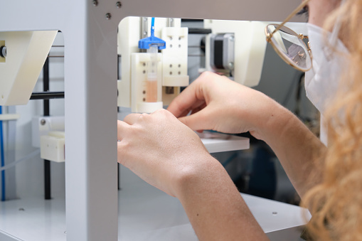 Researcher getting 3D bioprinter ready to 3D print cells onto an electrode. Biomaterials, tissue engineering concepts.