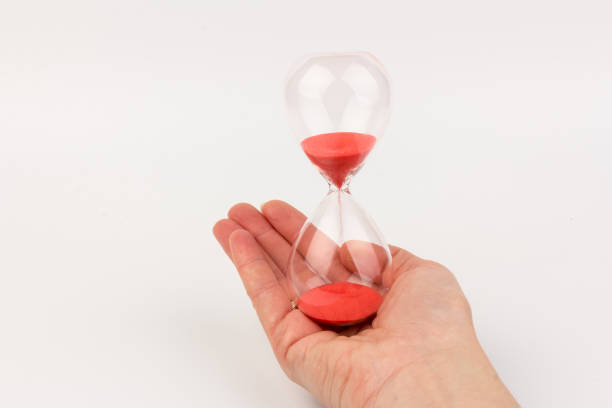 istock Hand holding a hourglass isolated on white background 1308575640