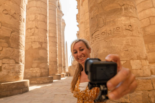 istock Blond woman takes selfie inside temple using action camera 1308576324