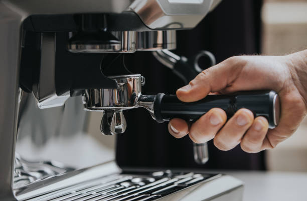 Hand Holding a Portafilter near beans grinder