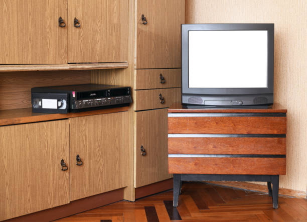 istock An old black TV with a white isolated screen for adding images and a VCR against old furniture from the 1980s and 1990s. 1308581459