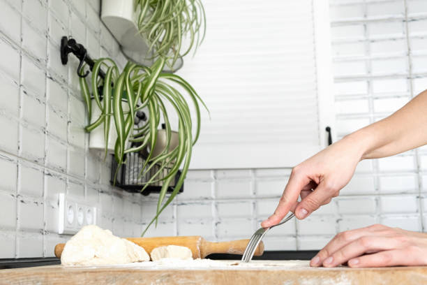 donna che perfora l'impasto con una forchetta per la cottura cieca. mani da donna che fanno pasticceria biscotto per crostata - cooking close up matzo food foto e immagini stock