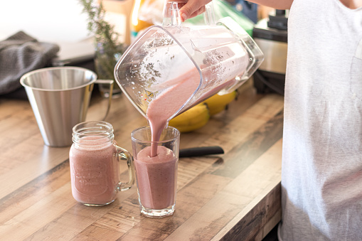 Woman pouring smoothie into a glass jar