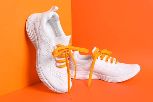 istock Stylish sneakers with shoe laces on orange background 1308583240