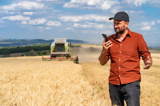 istock Farmer controlled harvest in his field and talking on a smart phone Harvest 1308583654