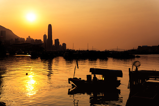 Sunset scene at the Causeway Bay Typhoon shelter in Victoria Harbour, Hong Kong with boats parked in the foreground and Kowloon side is seen at the background