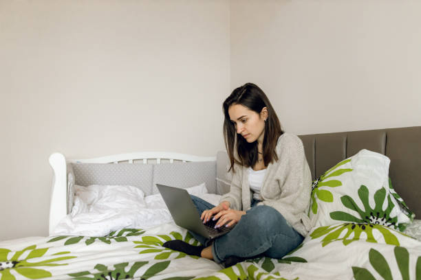 istock Young woman working online from her bedroom using laptop 1308589002