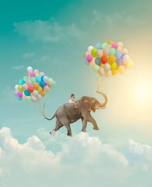 Photo of Little girl riding an elephant with balloons, flying in the sky; fantasy, metaphor, achievement concept