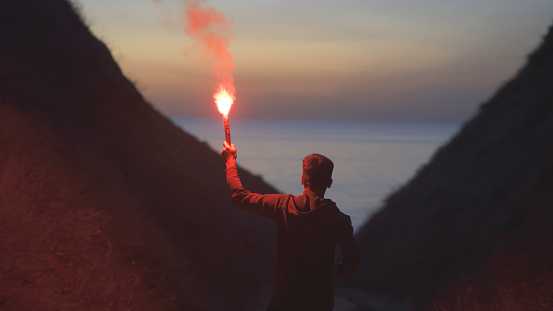The man with a fire stick walking in the mountains