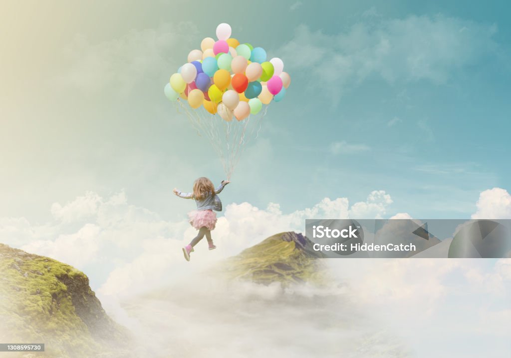 Little girl holding colorful balloons, jumping from one mountain top to the other; success/achievement concept, fantasy background with copy space Child Stock Photo