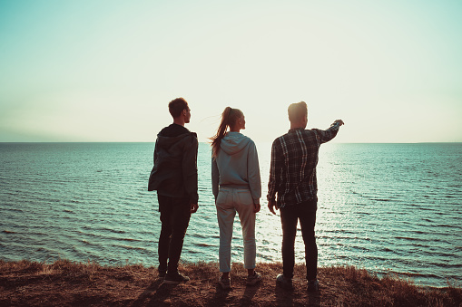 The three people standing on the mountain top near the sea