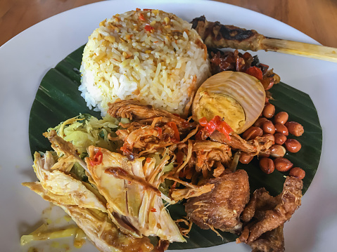 Close-up shot of spicy fried nasi campur ayam Bali. Variation side dish of shredded chicken , eggs, peanuts, vegetables and white rice.