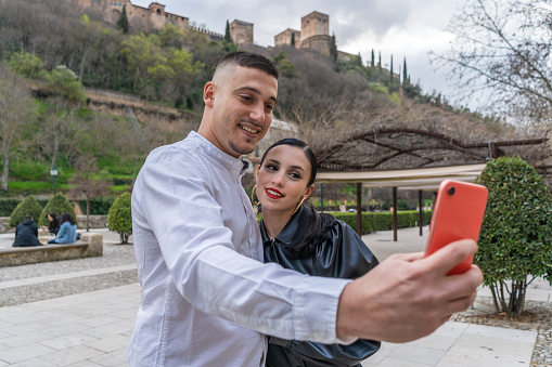 young couple in love taking a selfie with the Alhambra behind. Horizontal photography