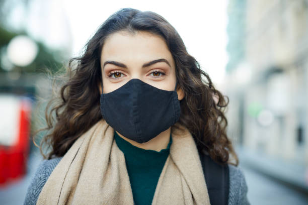 istock A young woman wearing a COVID protective facemask and looking at the camera. 1308599236