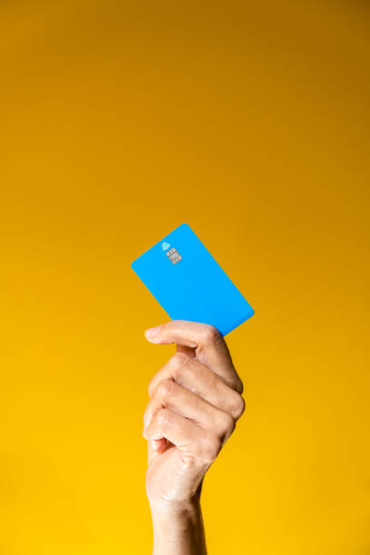 A female hand holds a blue credit card on an orange background and copy space. stock photo