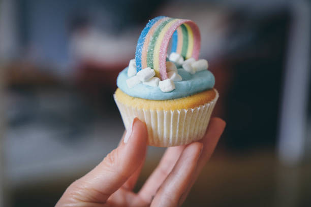 Woman hand holding  a rainbow cupcake