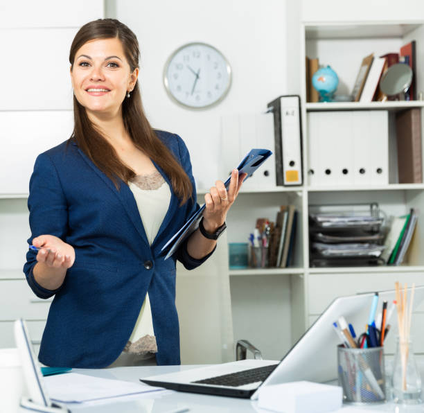 istock Young female office worker is standing with documents before signing it in office 1308604555