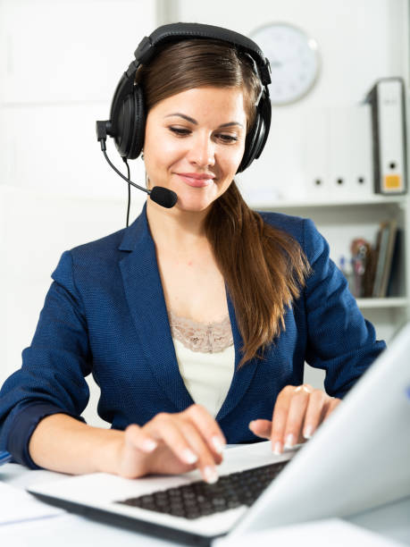 istock Smiling young female operator talking with customer using headset at company office 1308604590