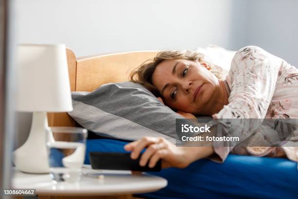 Turning Off The Alarm Clock On Her Smart Phone In The Morning Stock Photo - Download Image Now