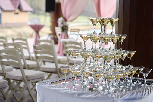 Stack of champagne glasses on table on wedding party reception outdoors. Champagne tower. Holiday concept
